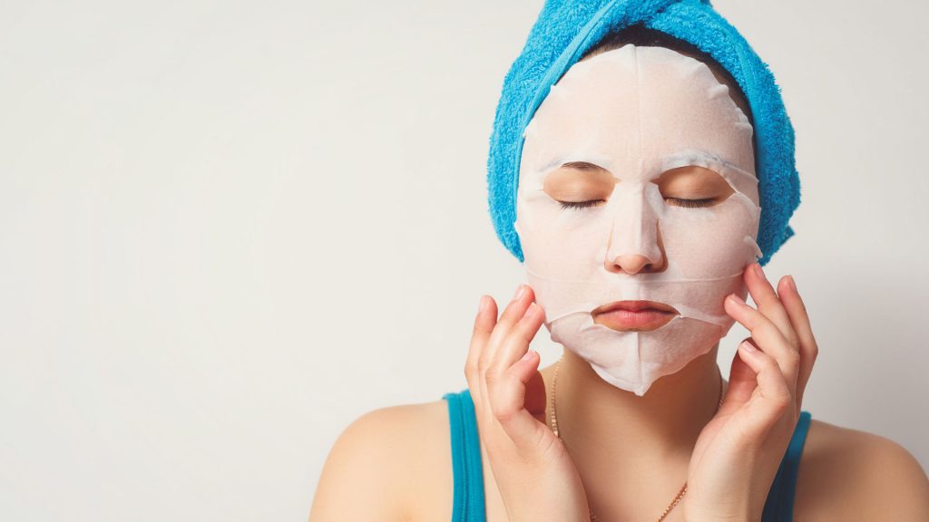 woman applying sheet facial mask