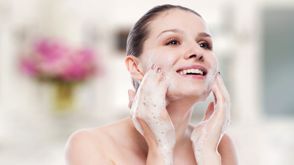 woman cleaning her face to get rid of pimples